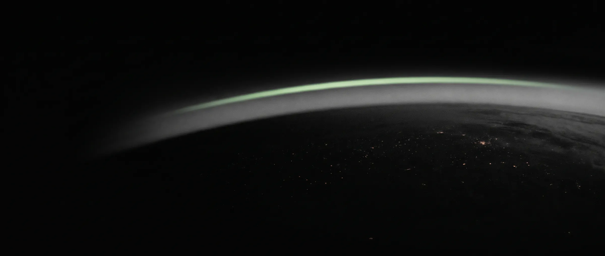 A green arc of light above a night horizon seen from altitude